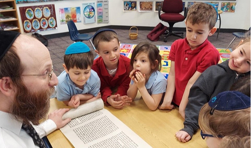 students sitting around teacher with scroll