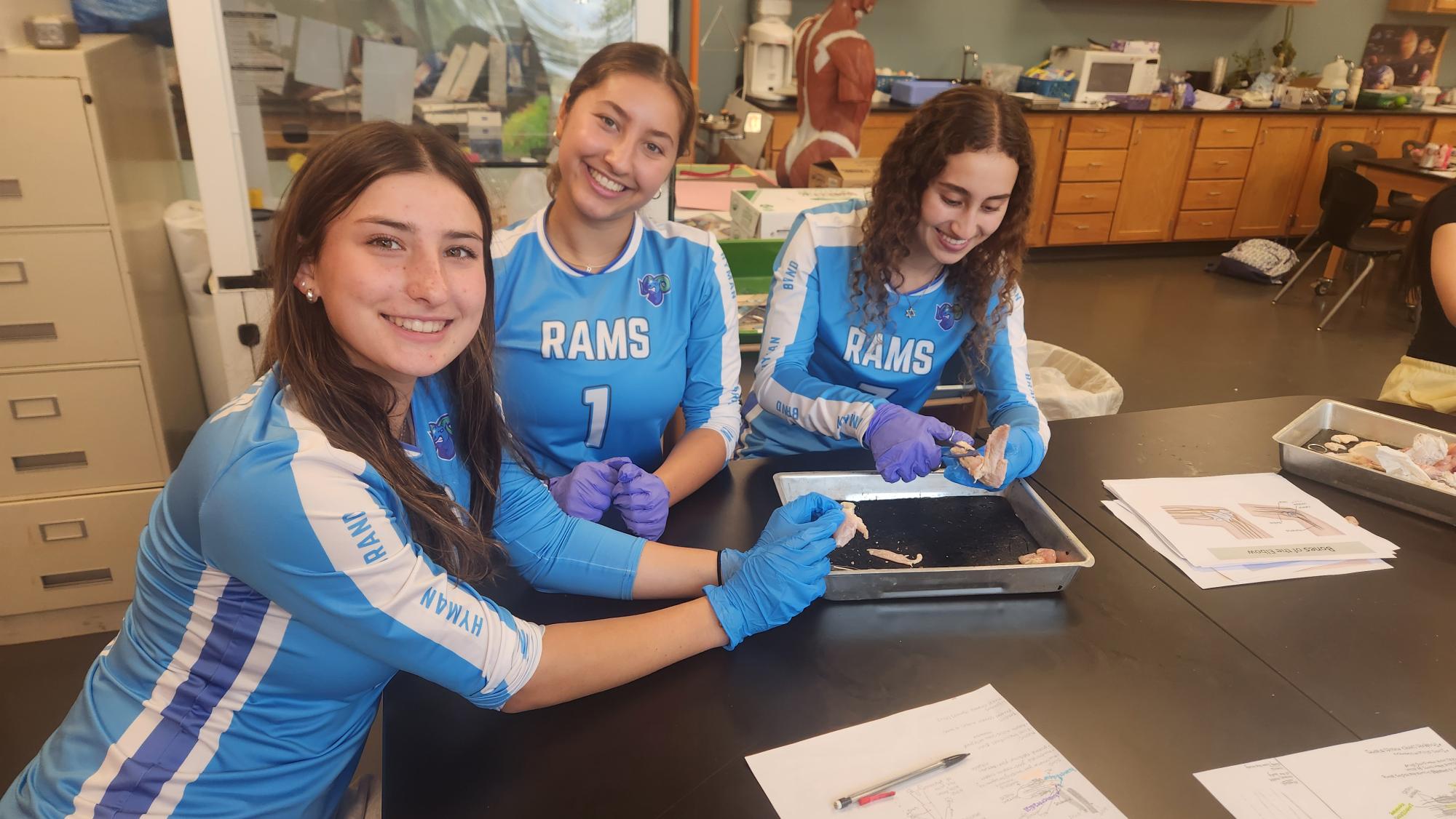 students smile while performing a dissection in the science lab